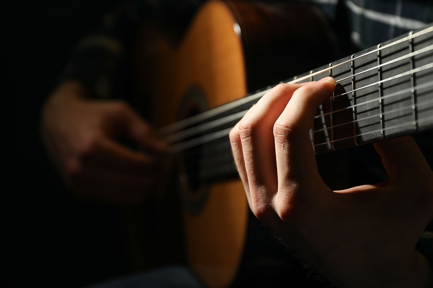 Man Playing On Classic Guitar Against Dark Backgro 5vpn3sv.jpg